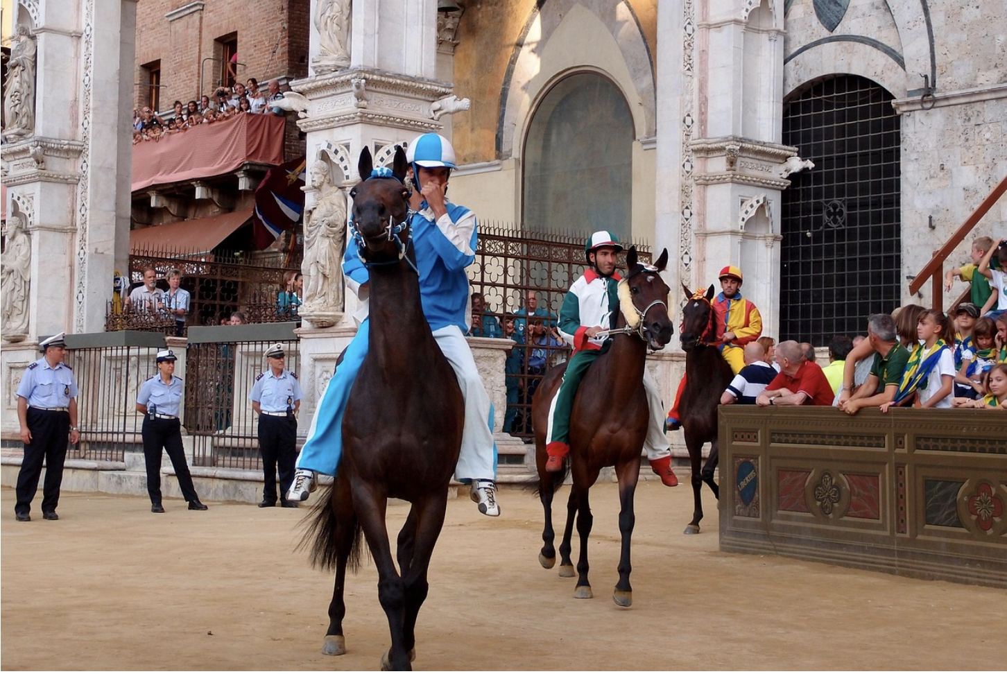 Jockeys are walking their horses to the races in Palio